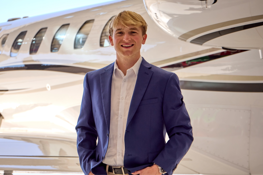 Smiling professional in blue suit standing by private jet in hangar, executive aviation and luxury business travel