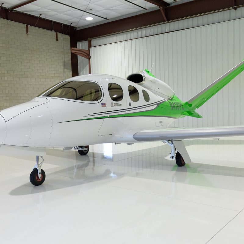 White and green Cirrus Vision Jet SF50 in hangar, single‑engine light private jet