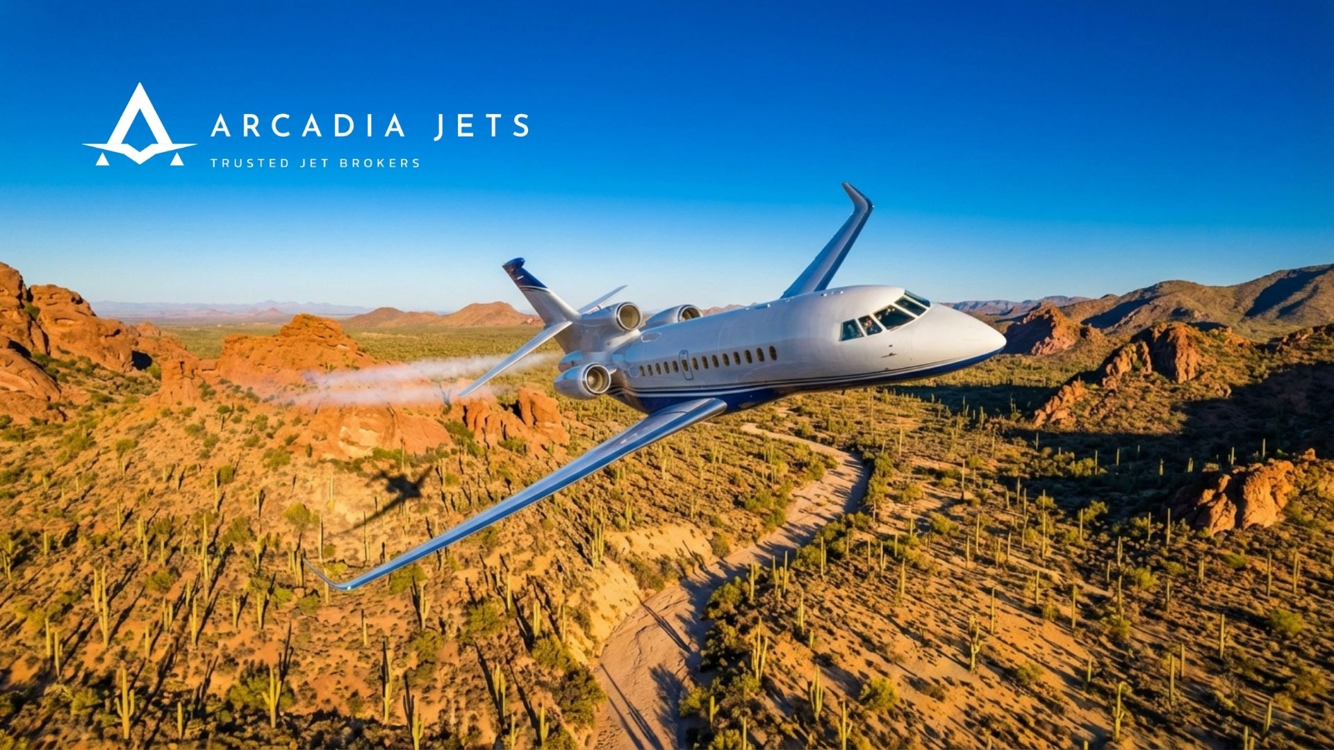 Arcadia Jets private jet soars over sunlit desert mountains—trusted jet brokers for luxury business air travel.
