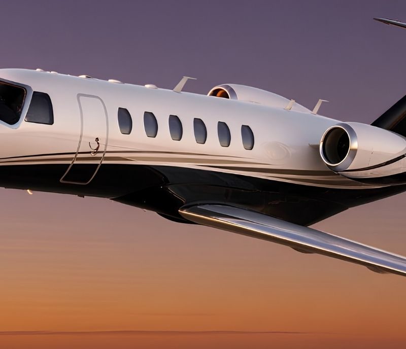 Private jet charter in flight at sunset, luxury business aircraft cruising under purple-orange sky