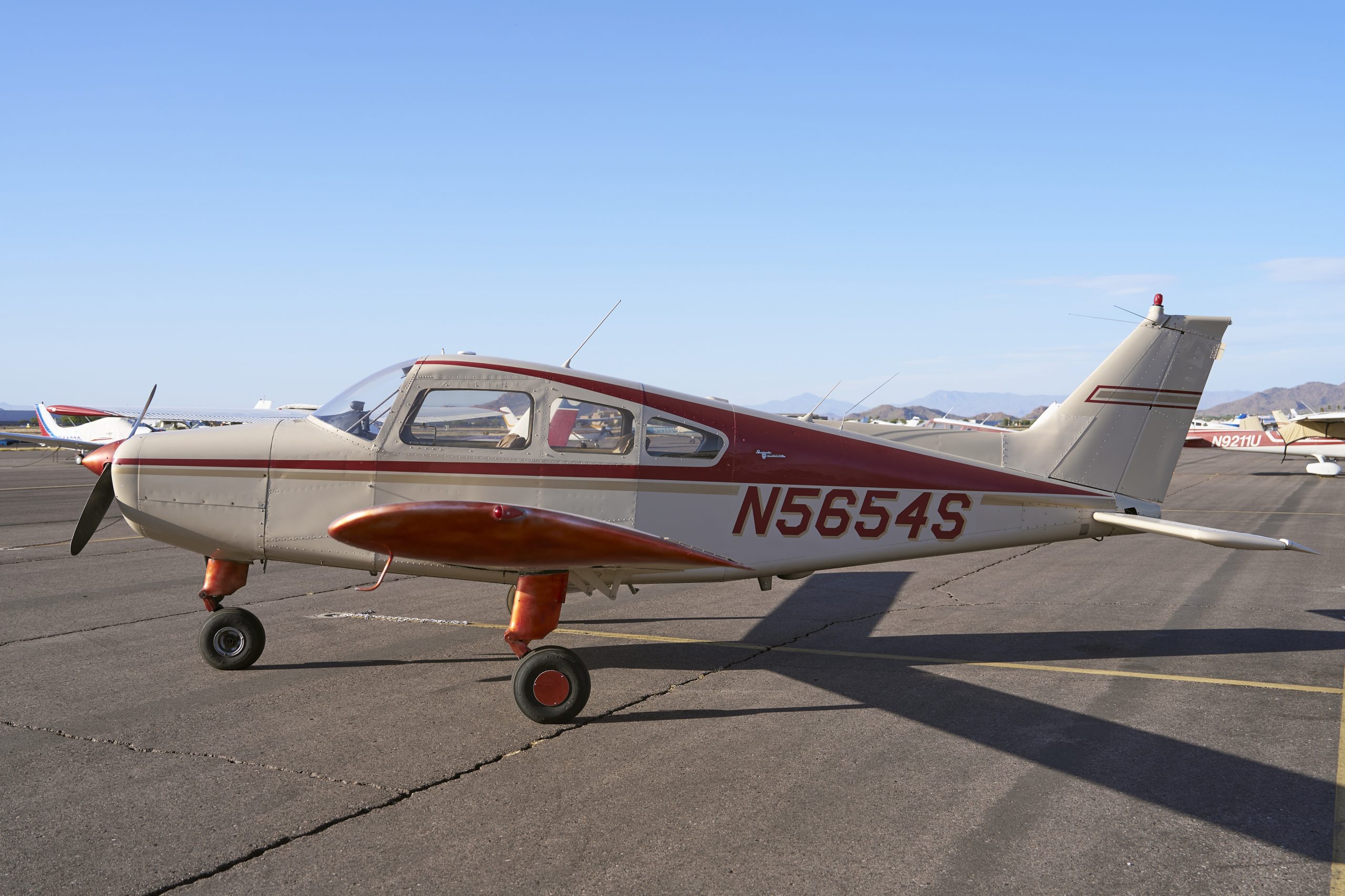 Single-engine propeller plane N5654S parked on sunny airport tarmac, general aviation light aircraft