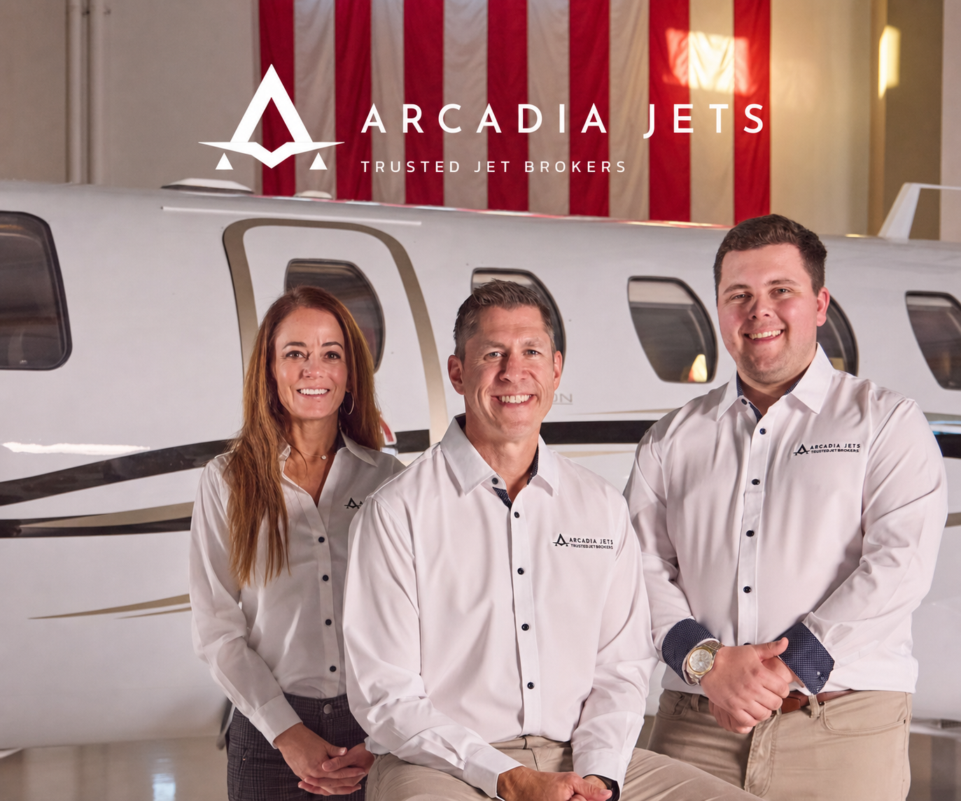 Arcadia Jets trusted jet brokers team in front of private jet in hangar with American flag